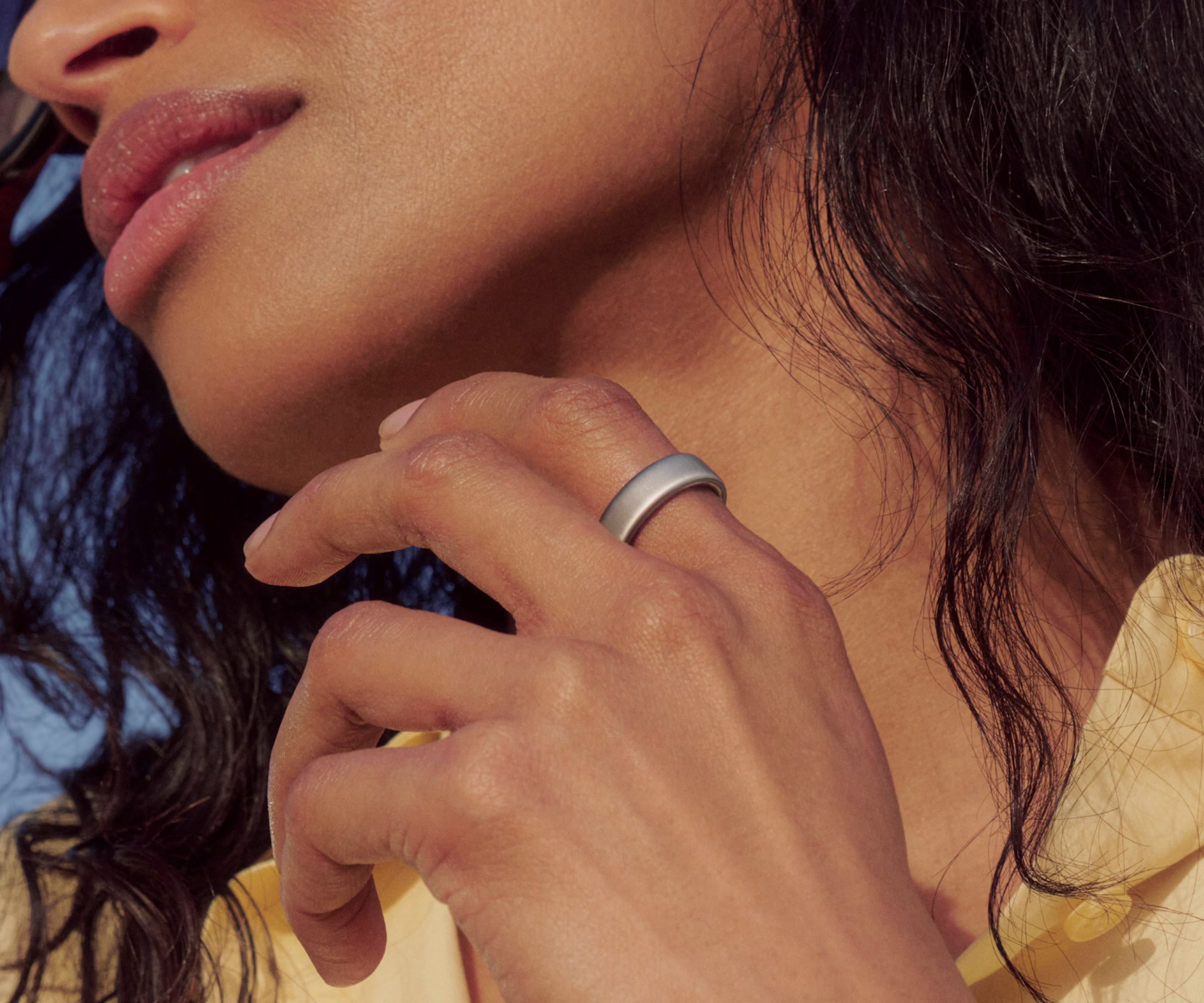 Close up of a person lifting their hand in front of their chest with a Brushed Silver Oura Ring 5 on their finger