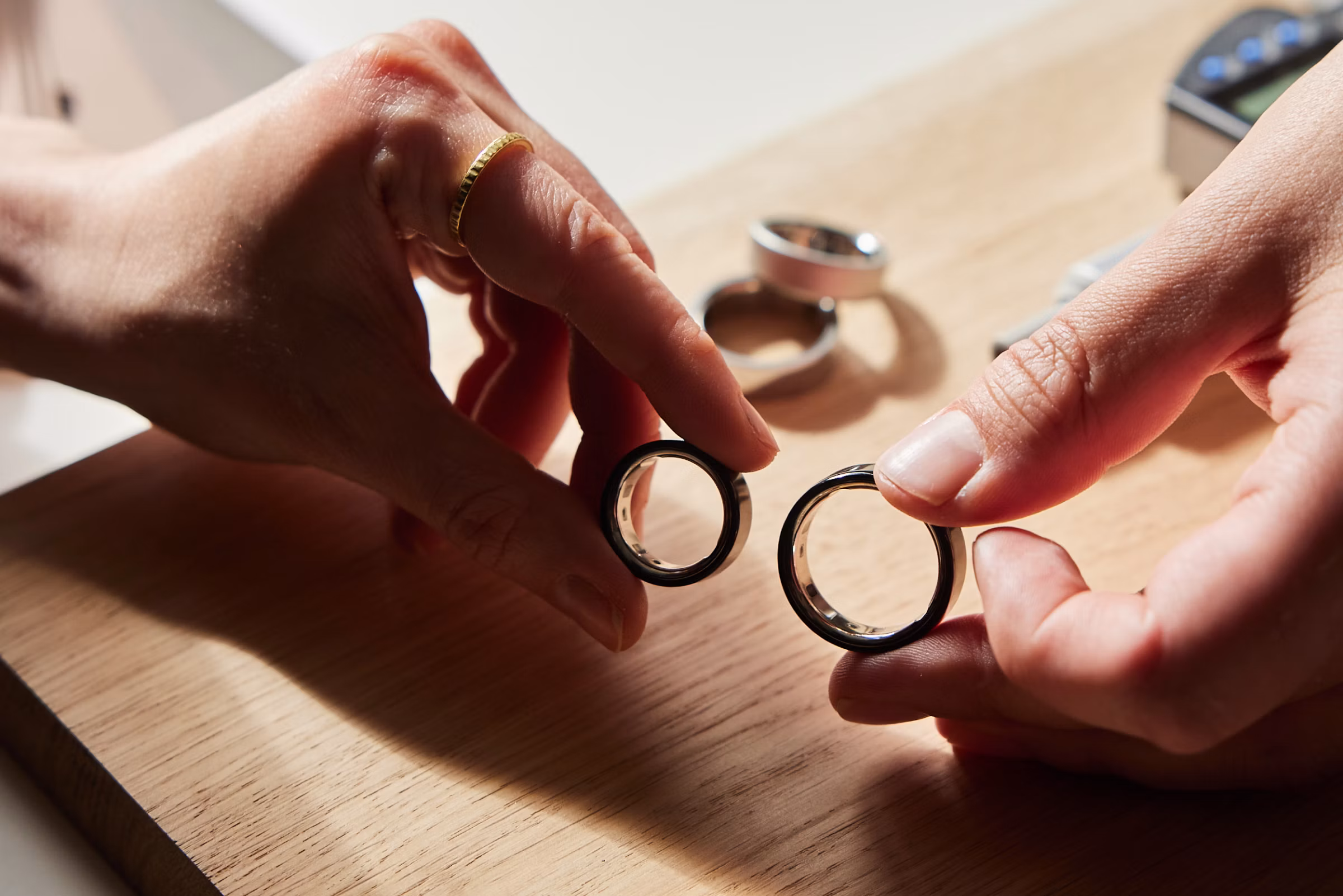 One hand holding the smallest size Oura Ring and another hand holding the largest size Oura Ring