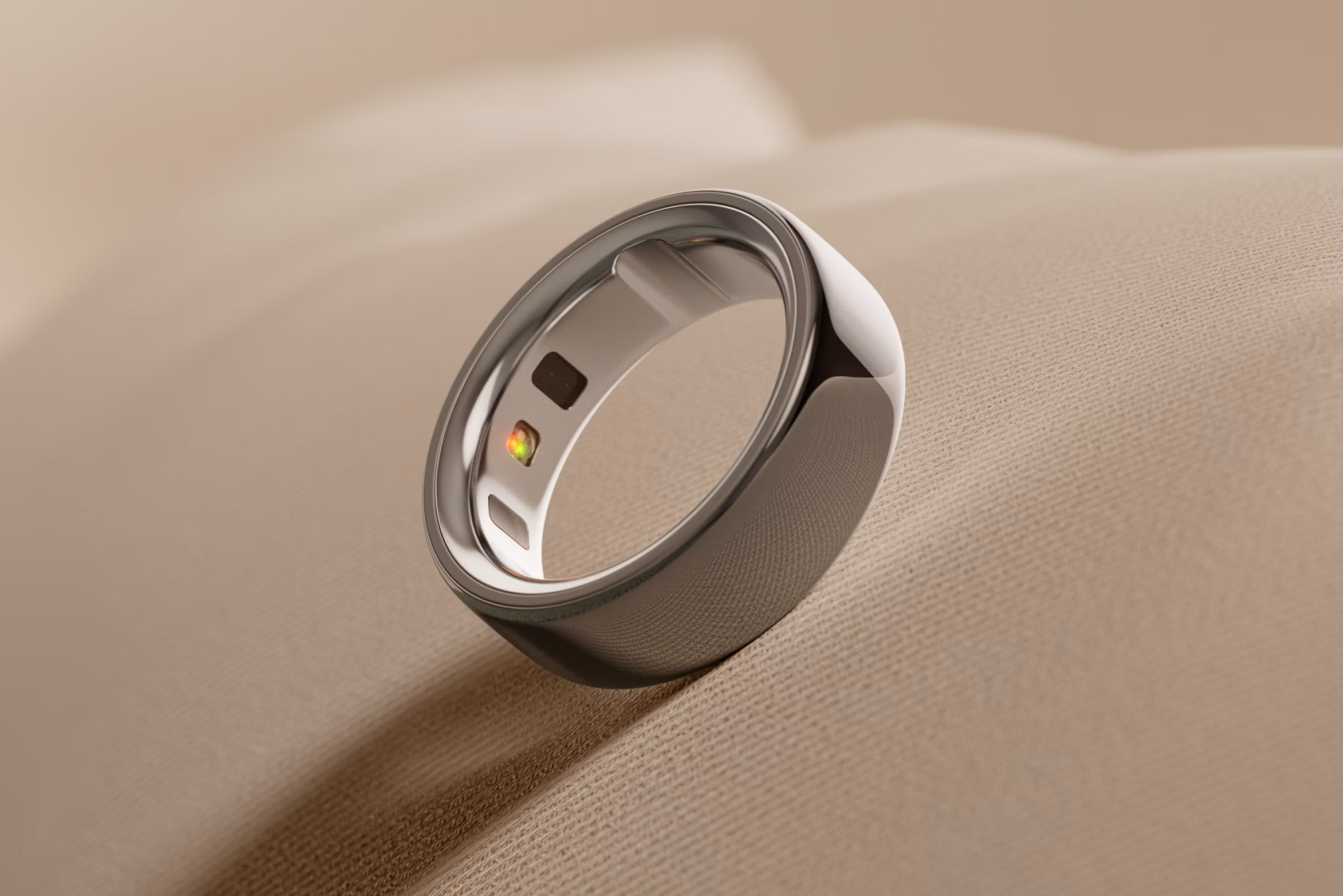 An Oura Ring 4 in the silver finish with a creamy beige background