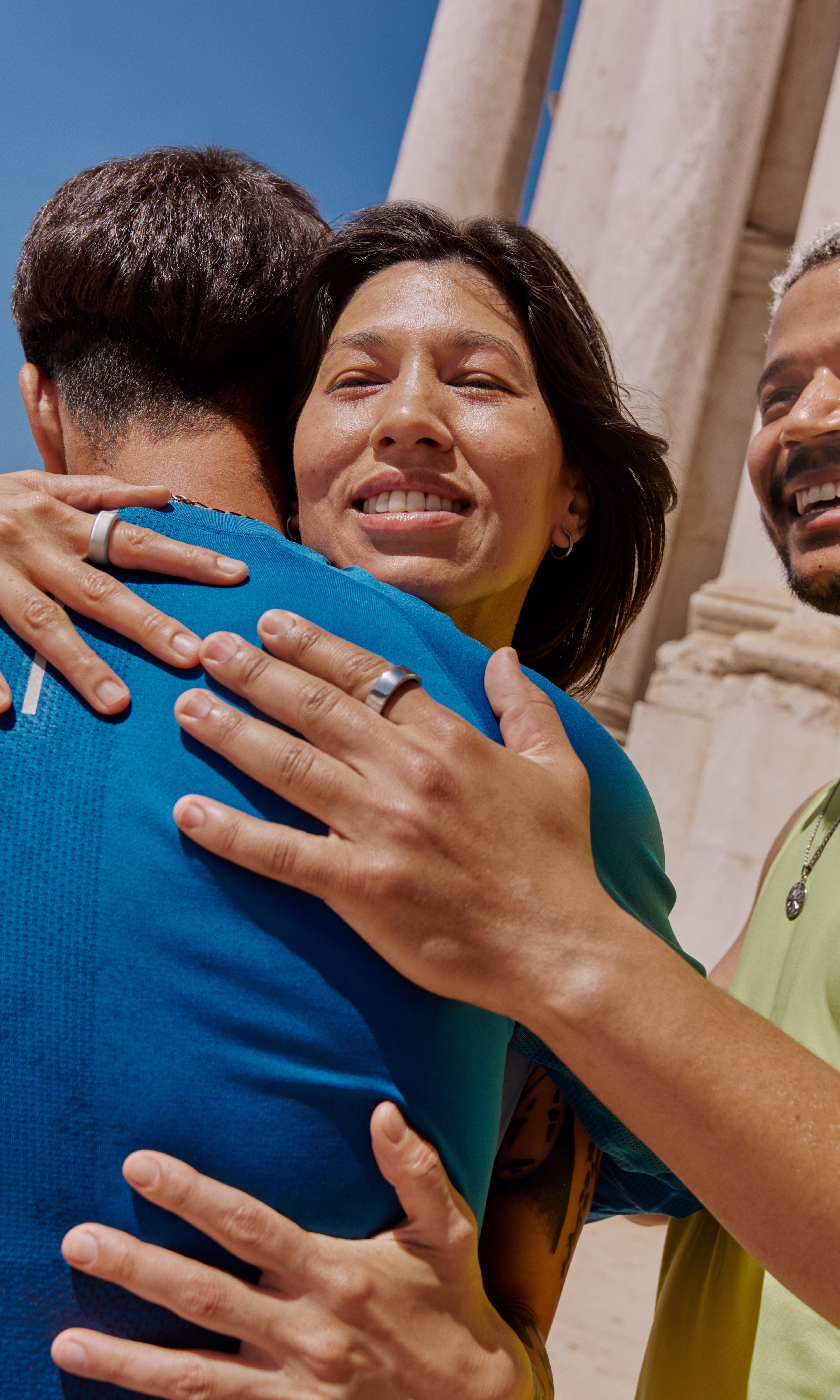 Three people smile and greet each other while wearing Oura Rings