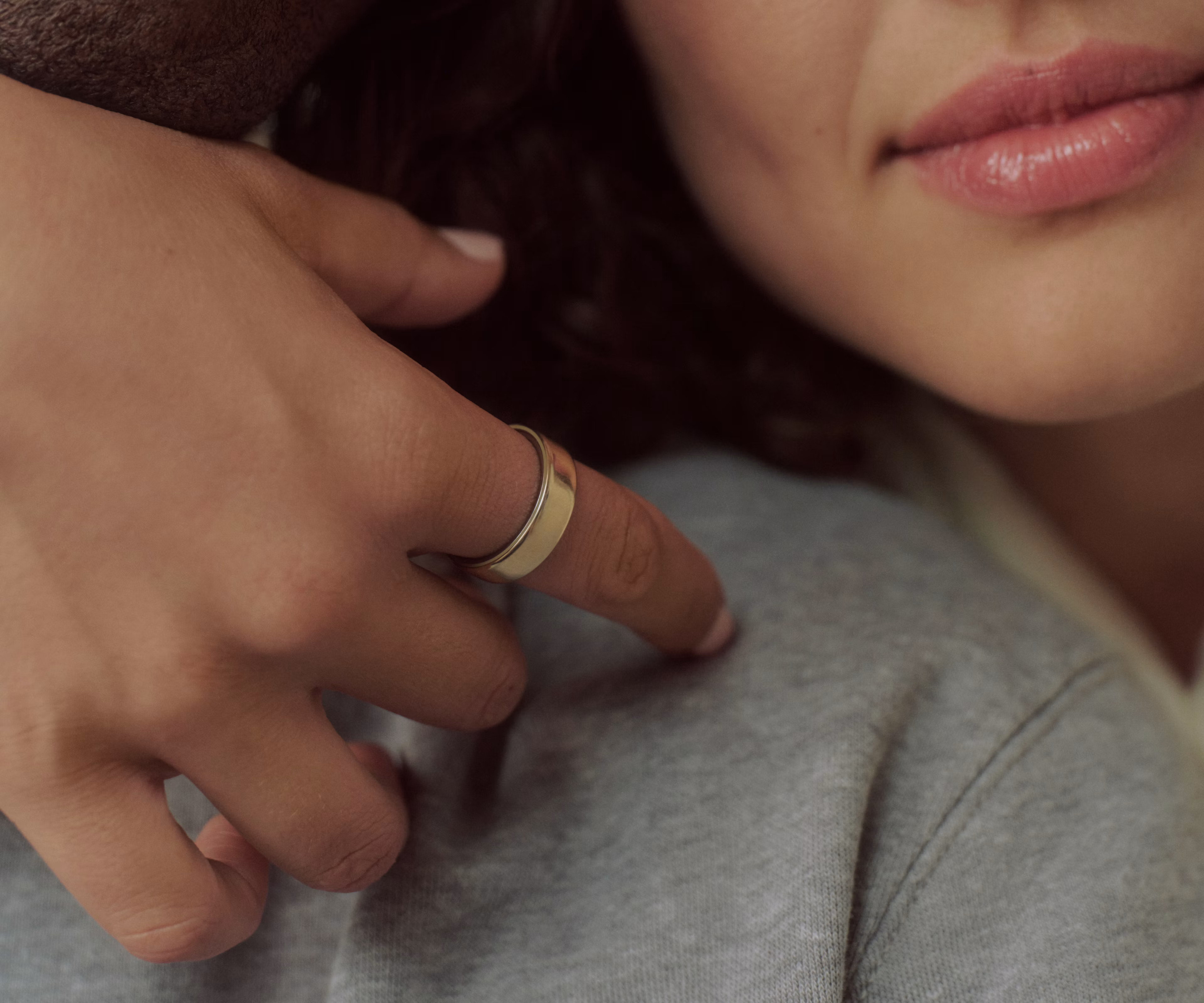 Close-up of a person's hand resting on another's shoulder, wearing a Gold Oura Ring 5.