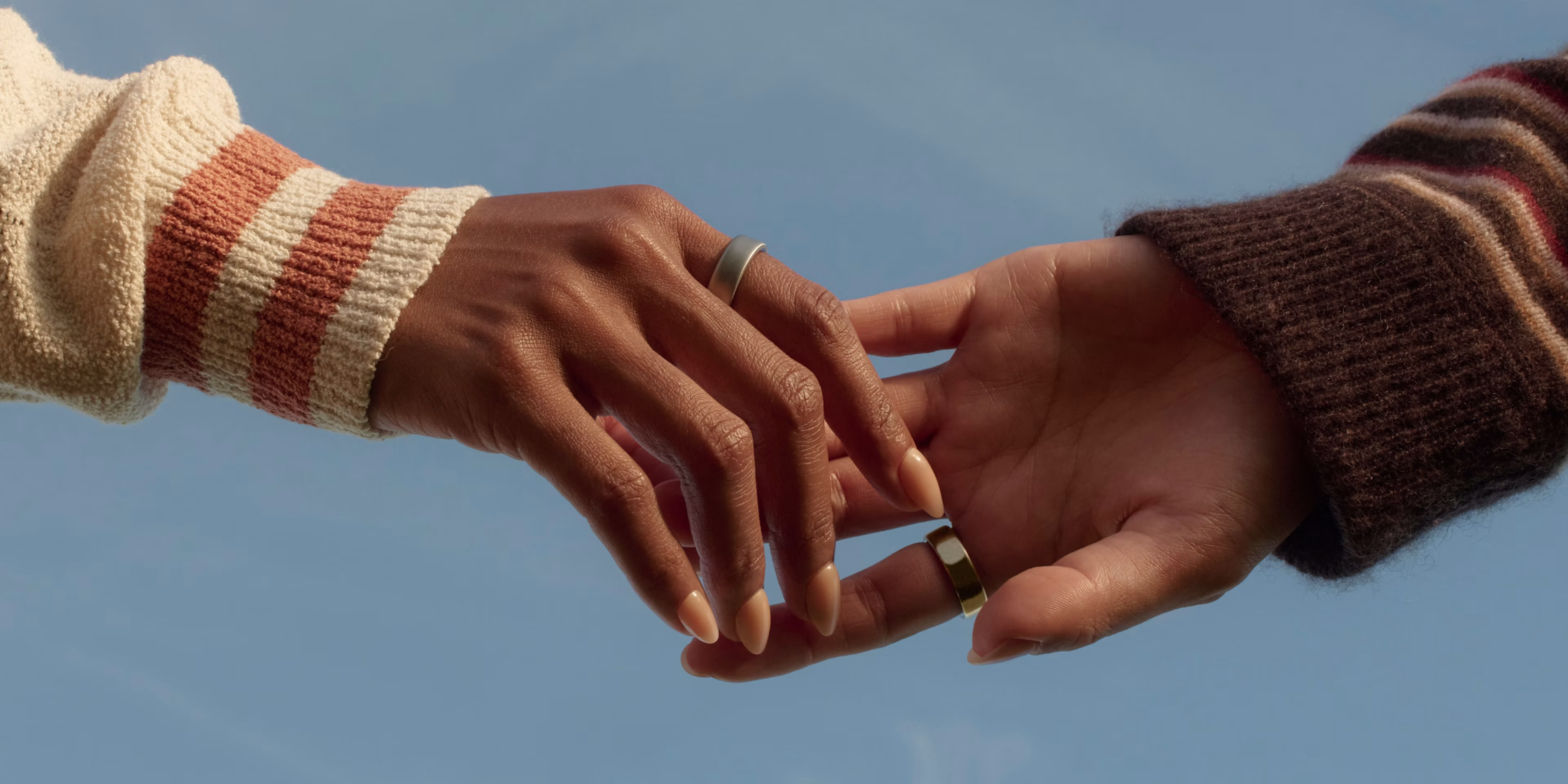 Close-up of two people's hands featuring Oura Rings on their index fingers