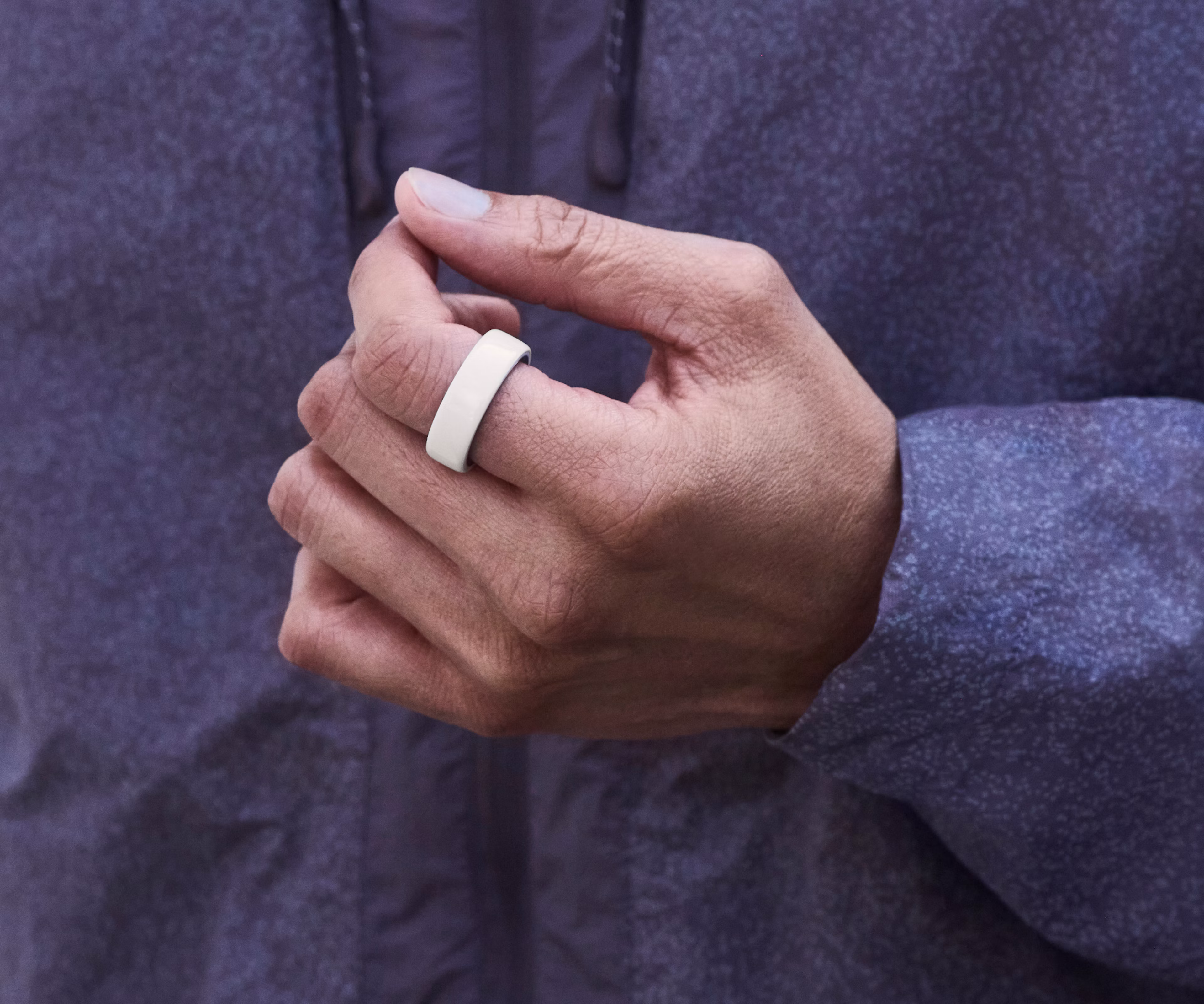 Close up of a person's hand with a Cloud Oura Ring 4 Ceramic on their finger