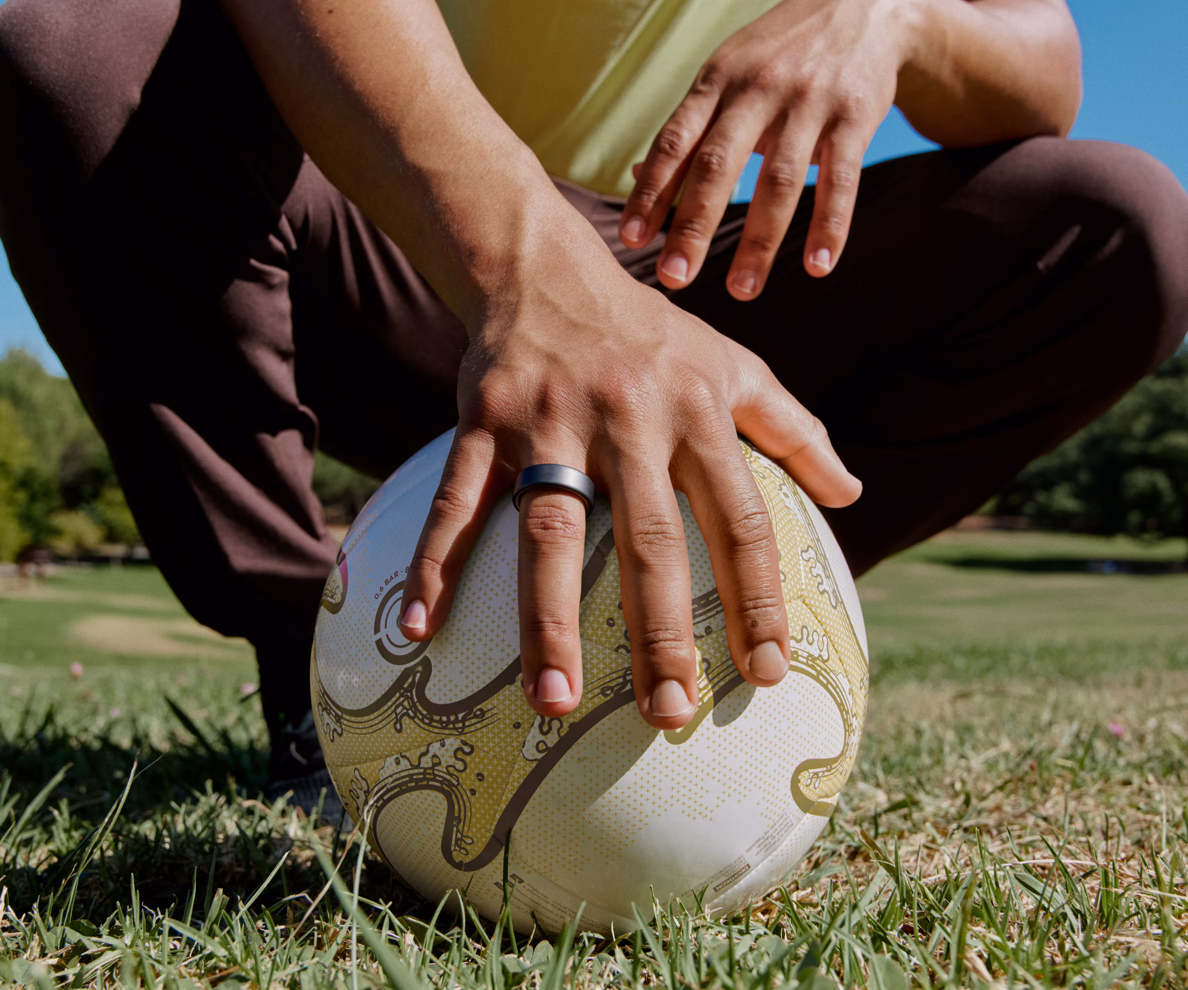 A person wearing a Stealth Oura Ring 4 holding a soccer ball