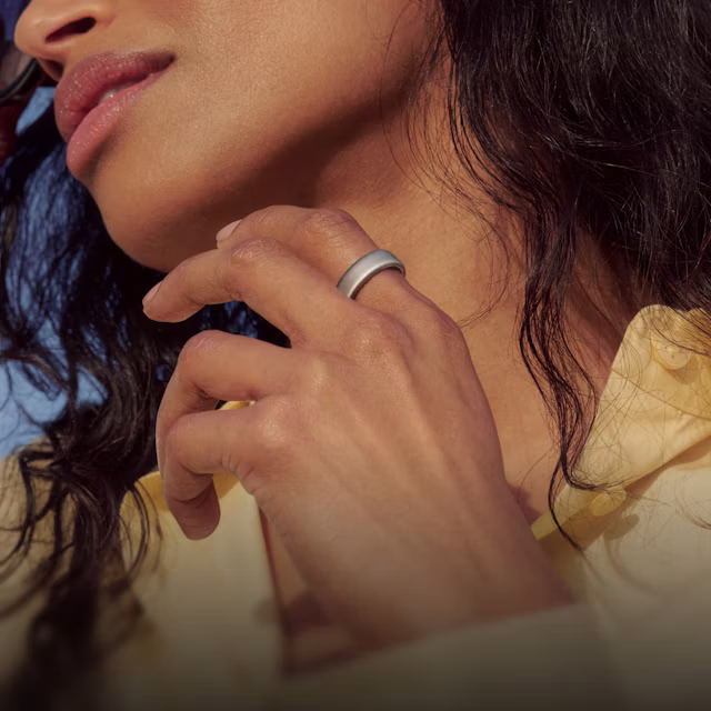 Close up of a person lifting their hand in front of their chest with a Brushed Silver Oura Ring 5 on their finger
