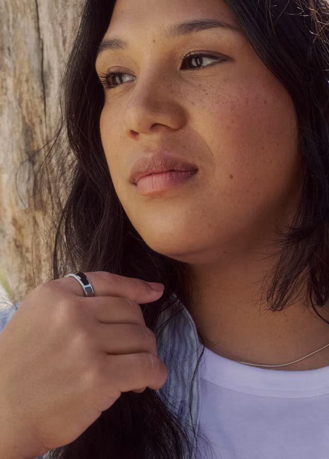 Close up of a woman wearing an Oura Ring 5 in Silver finish while gazing to the left