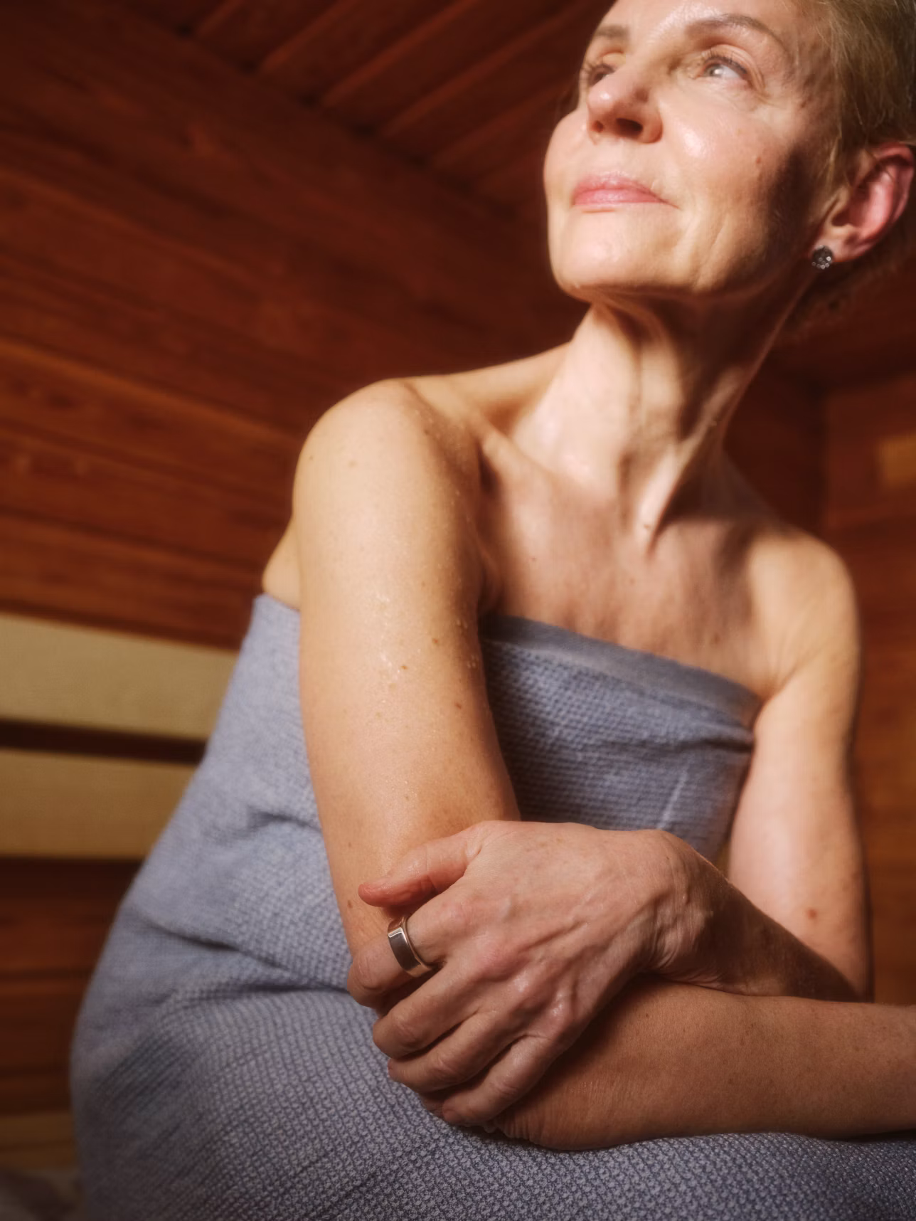 A woman sitting in a sauna wearing an Oura ring.