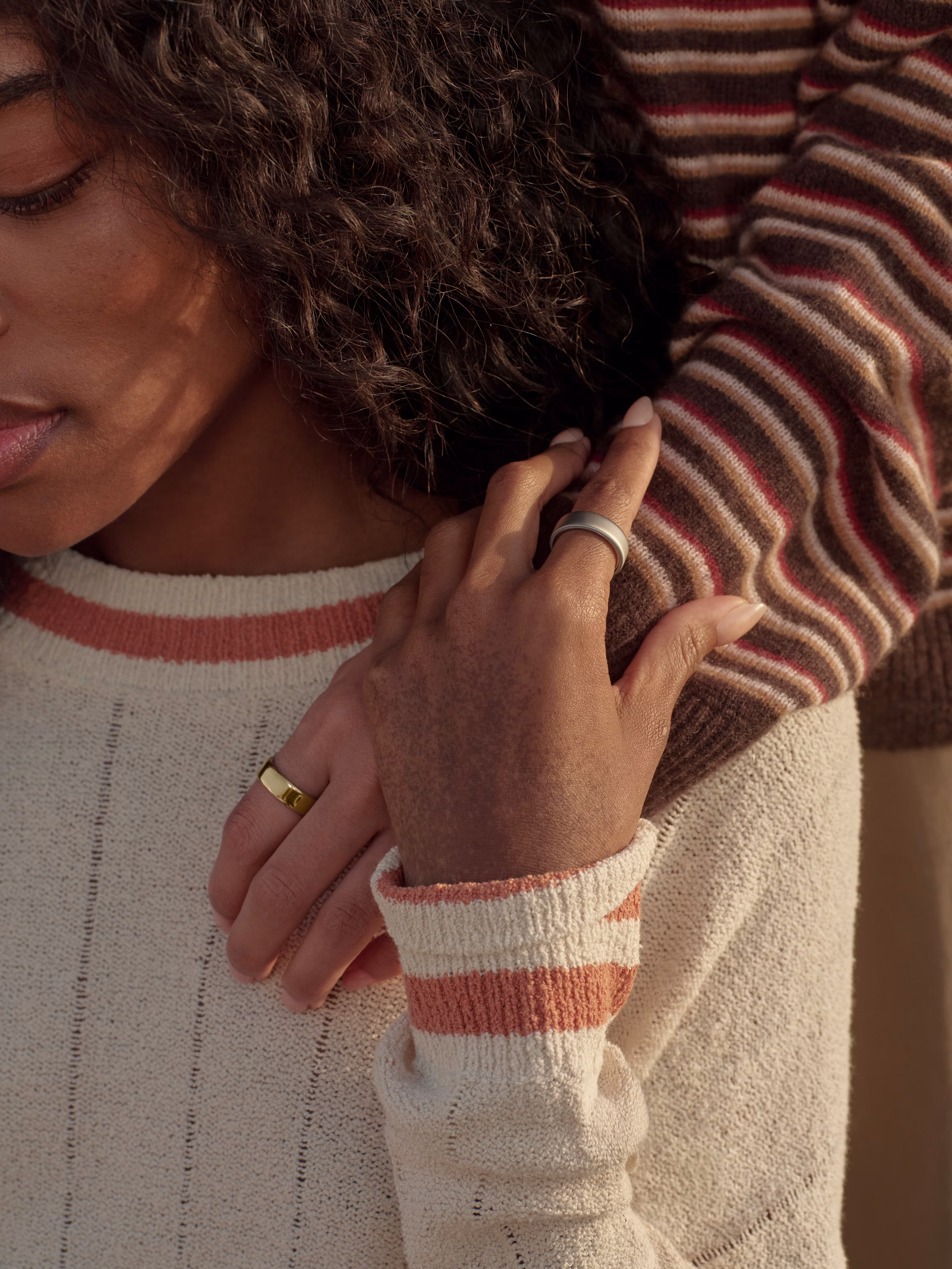 Woman in striped sweater with Gold Oura Ring resting her hand gently on a loved one's shoulder.